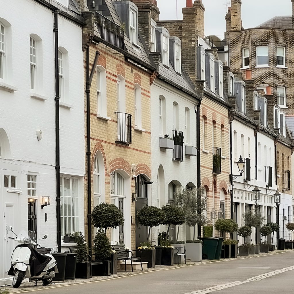 Pastel coloured Clabon Mews, London home facades with white vespa parked infant