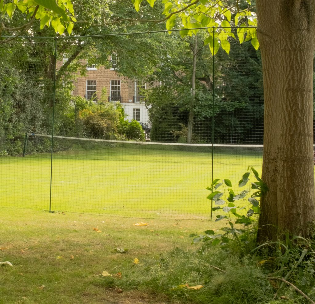 A grass tennis courts set within private gardens in London